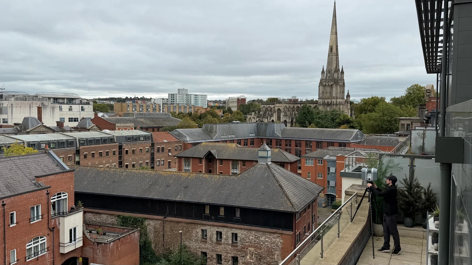 Geo Scan surveyor operating a laser scanner on a high-level balcony in Bristol.