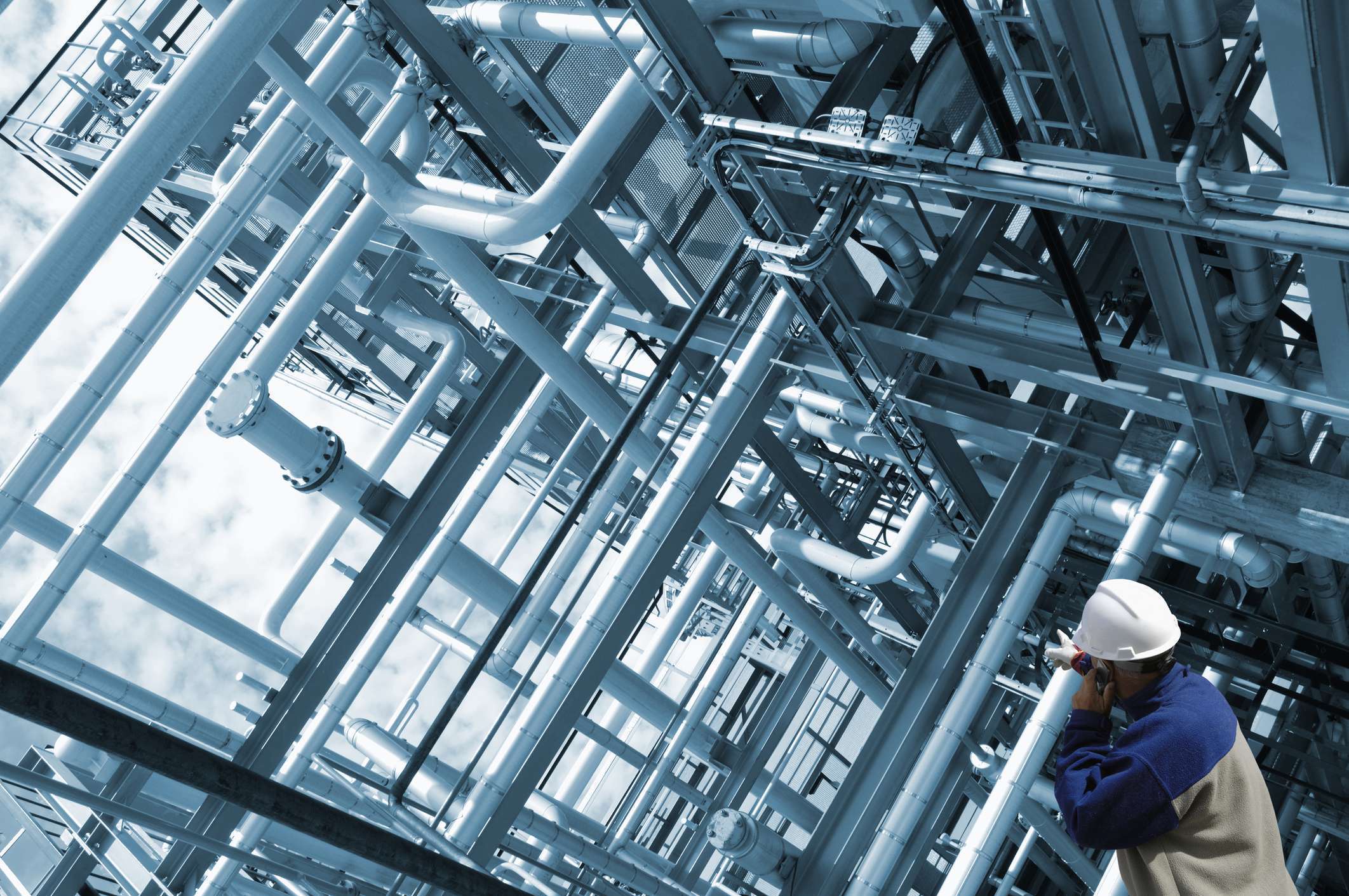 An engineer standing in front of a network of pipelines, focusing on complex and detailed measured surveys.